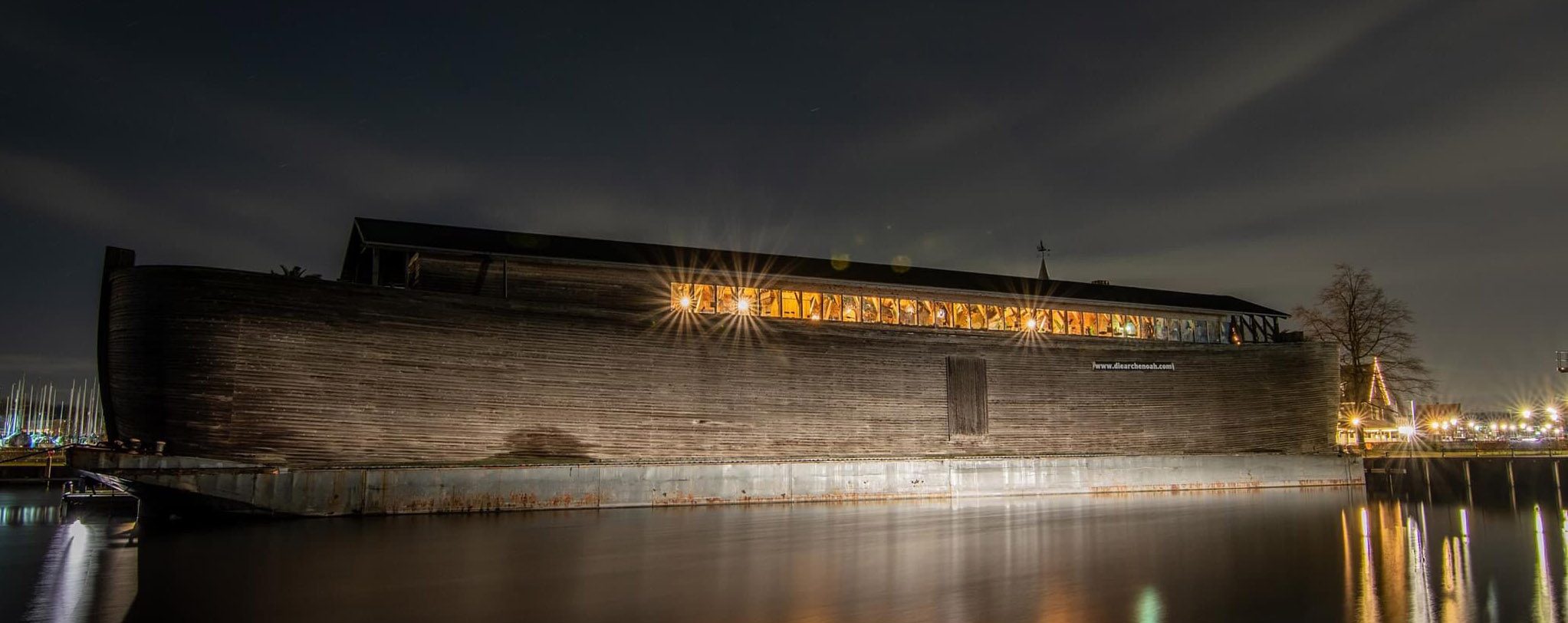 De Ark van Noach bij avond, met verlichte ramen langs de volle lengte van het schip
